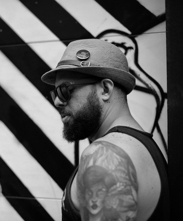 Retrato en blanco y negro de Edgardo Herrera, de perfil, ante un muro de rayas diagonales.