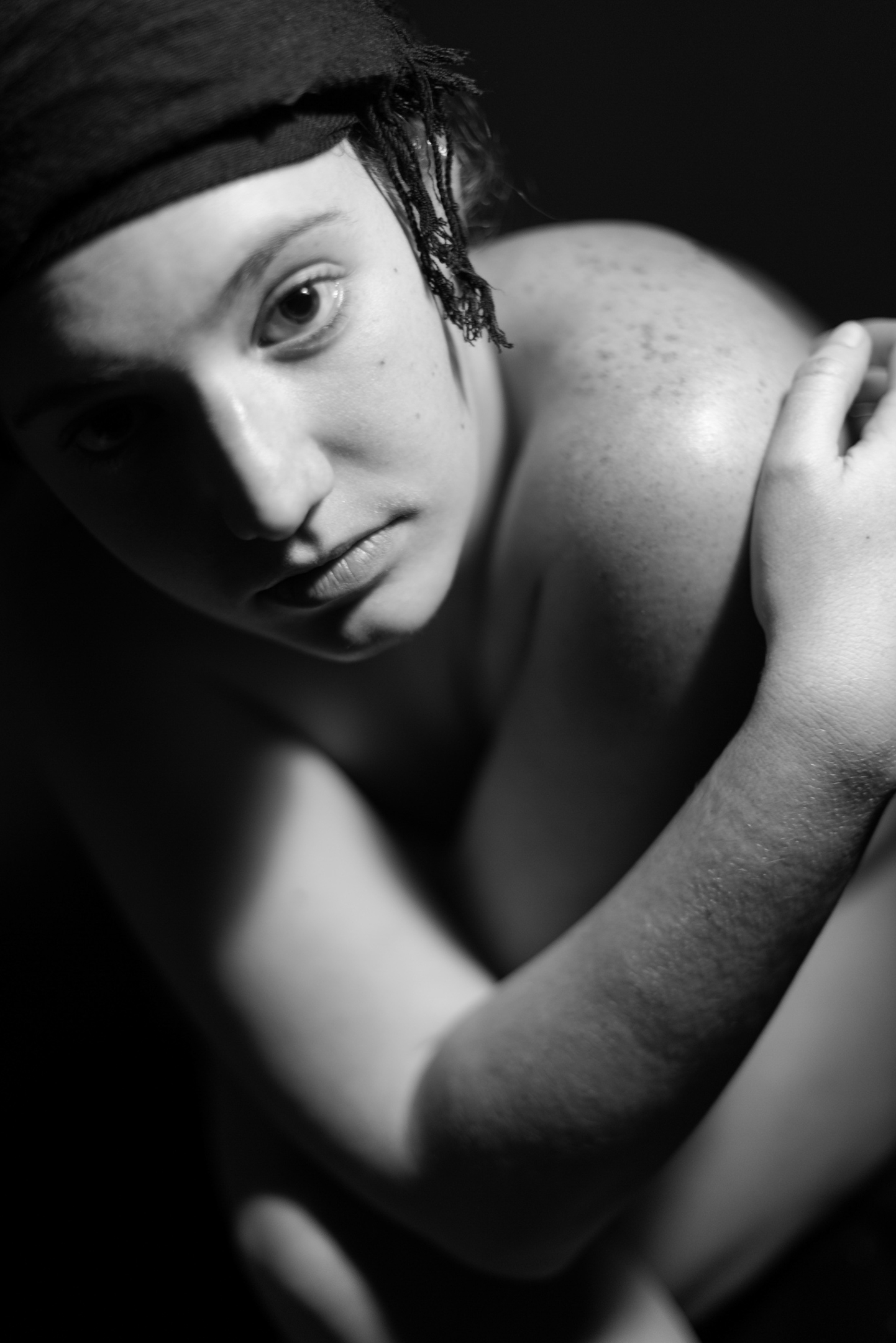 Retrato en blanco y negro de una persona con un pañuelo oscuro en la cabeza, la mirada hacia la cámara y una mano sobre el hombro.